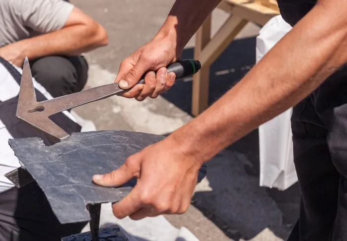 Perforado de una pizarra con martillo de pizarrero antes de clavarla al rastrel